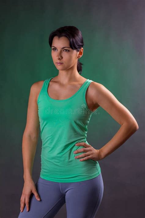 beautiful athletic woman fitness woman standing posing on a gray background with a green