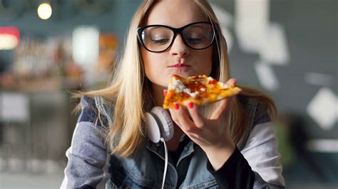 Hipster Girl Eating Pizza In The Restaurant And Smiling To The Camera