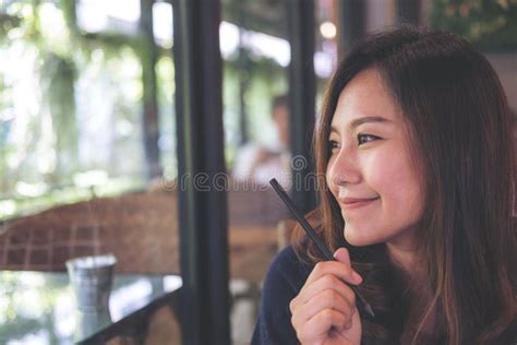 Closeup Portrait Image Of A Beautiful Asian Woman With Smiley Face Sitting In Modern Cafe While