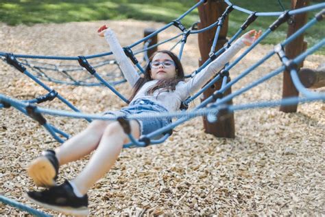 Caucasian Girl Lying Down Rides On A Rope Swing In The Park At The Playground Stock Image