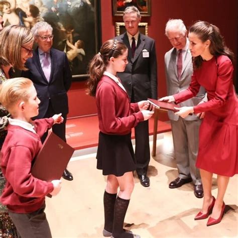 la reina letizia recibe un regalo de manos de una niña en presencia del príncipe carlos en la