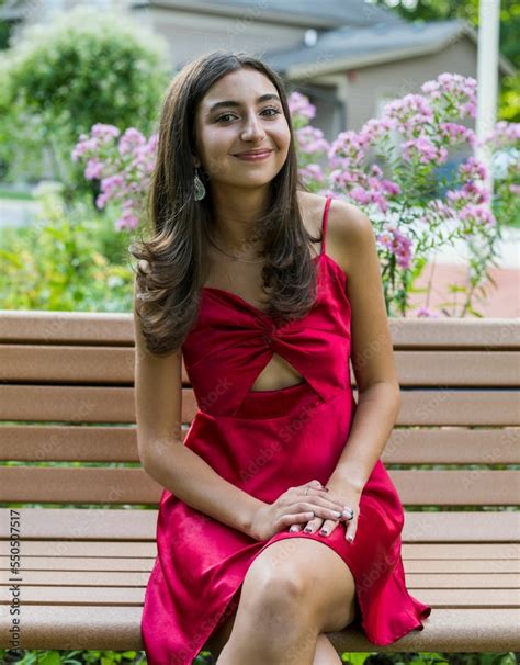 Zdjęcie Stock Teenage Girl Sitting On Park Bench With Red Dress