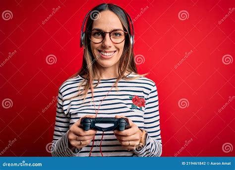 Young Blonde Gamer Woman Using Gamepad Playing Video Games Over Red