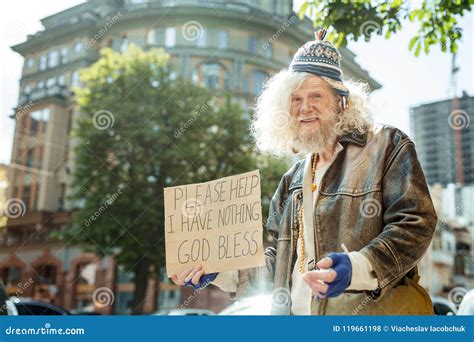 A Homeless Man With Gloves And A Dirty Face Is Smokin