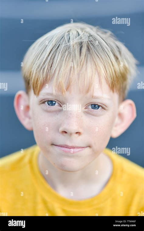 Close Up Portrait Of Boy With Blond Hair Standing On Road Stock Photo