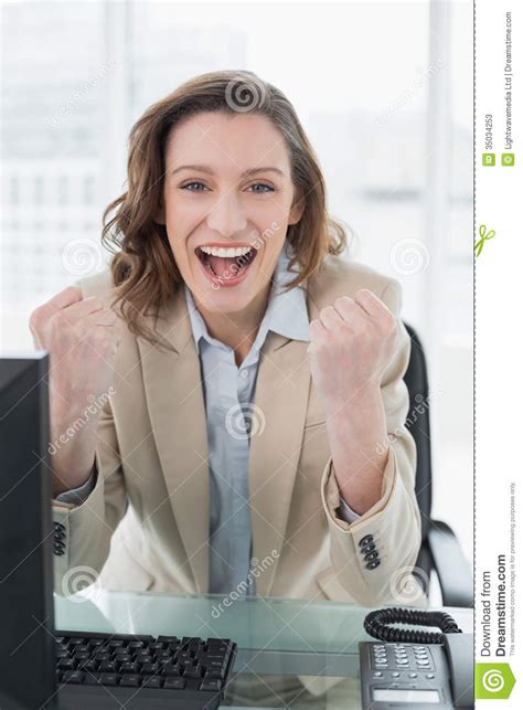 Businesswoman Cheering With Clenched Fists In Office Stock Image