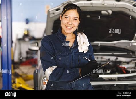 Smiling Mixed Race Female Car Mechanic Wearing Overalls Making Notes