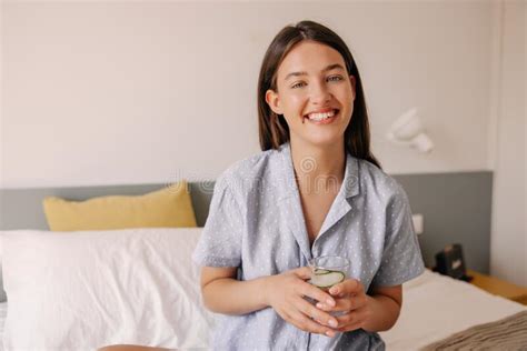 Happy Young Caucasian Woman Wearing Grey Pajamas Smiling At Camera Sitting Indoors Stock Image