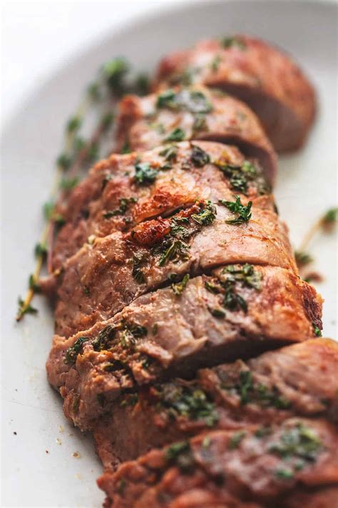 Pork tenderloin is a lean cut of meat. close up view of roasted sliced pork tenderloin with herbs ...
