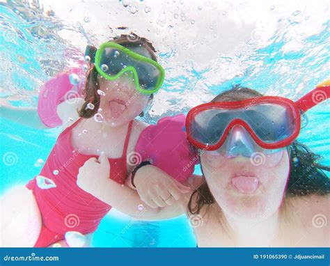 Happy Mother And Daughter Sticking Out Their Tonge Swim Underwater In A Swimming Pool Holidays