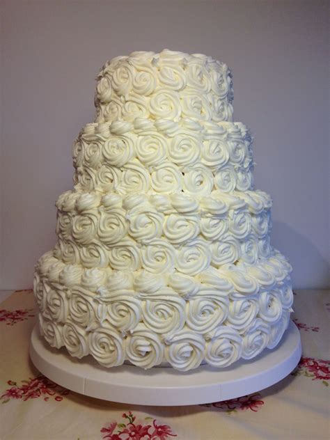 A Beautiful Four Tier Wedding Cake Covered In White Buttercream Roses