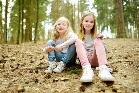 Two Cute Young Sisters Having Fun During Forest Hike On Beautiful Early