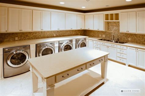 A Large Kitchen With White Cabinets And Washer And Dryer In The Center