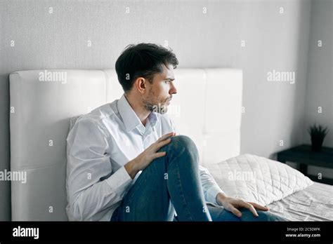 Sad Man Sitting In Bed Indoors And Looking Aside Loneliness Stock Photo