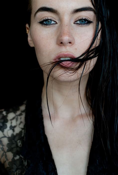 A Woman With Long Black Hair And Blue Eyes Is Posing For The Camera Her Face Partially Obscured