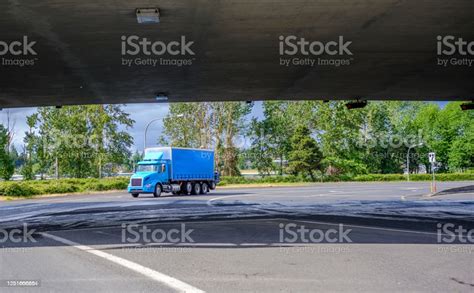 Blue Big Rig Day Cab Semi Truck With Long Box Trailer Running On The