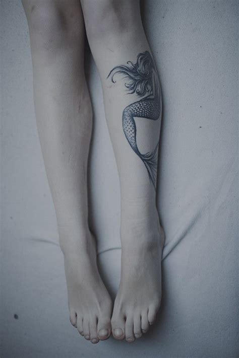 a woman with a tattoo on her leg laying in bed