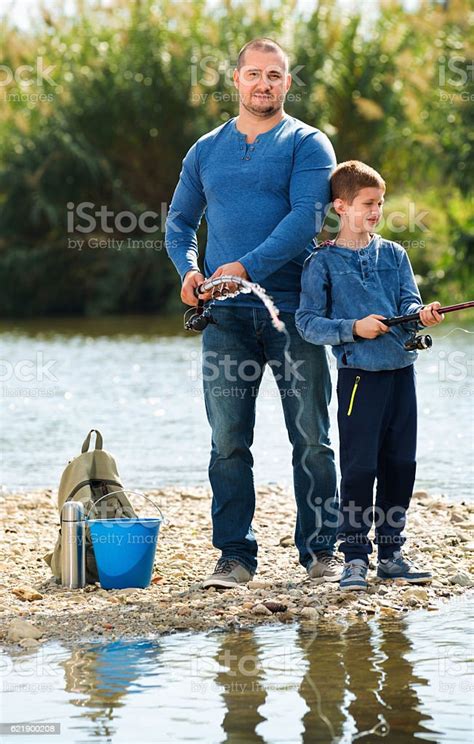 Portrait Of Father And Son Fishing With Rods Stock Photo Download