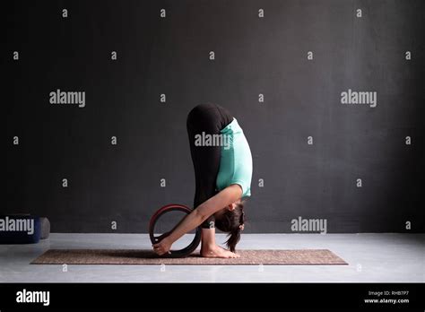 Woman Practicing Yoga Doing Forward Bend Exercise Using Wheel