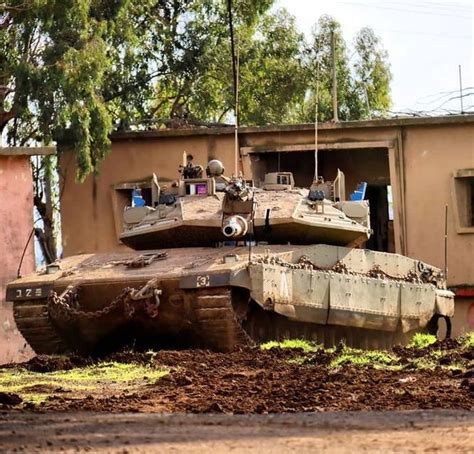 An Old Tank Sitting In Front Of A Building With Trees And Dirt On The