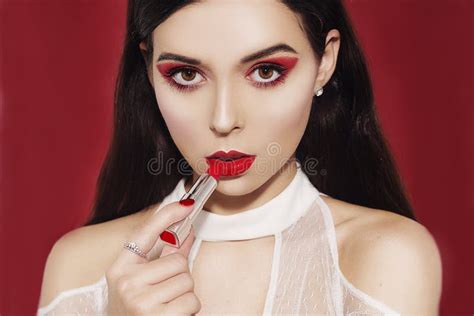 Beautiful Brunette With Professional Red Make Up On A Red Background