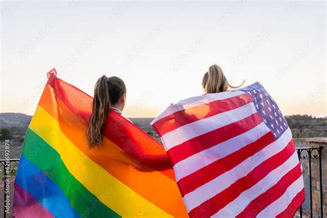Back View Unrecognizable Lesbians Couple Holding Lgtb Rainbow Flag And American Flag At Sunset