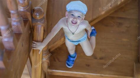 Cute Little Boy Stands On The Stairs And Looks Up Stock Photo Aff