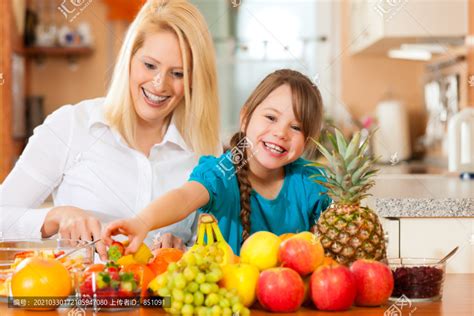 健康饮食 母亲和孩子坐在厨房里，早餐吃不同种类的水果摄影素材汇图网