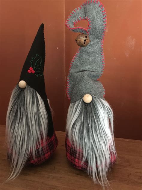 Two Gnomes Sitting On Top Of Each Other Wearing Black And Grey Hats