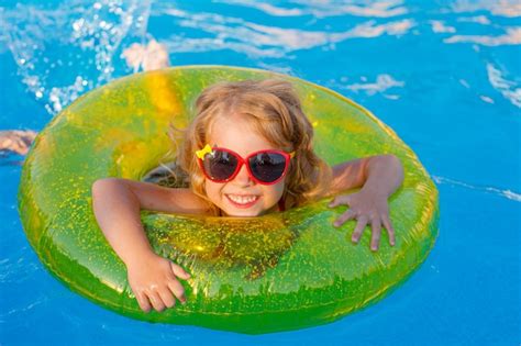Маленькая девочка в солнцезащитных очках и купальнике плавает в