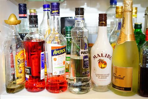 liquor bottle collection on white shelf free image | Peakpx
