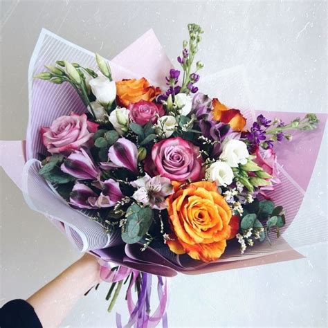 A Bouquet Of Flowers Is Being Held By Someones Hand On A White Surface