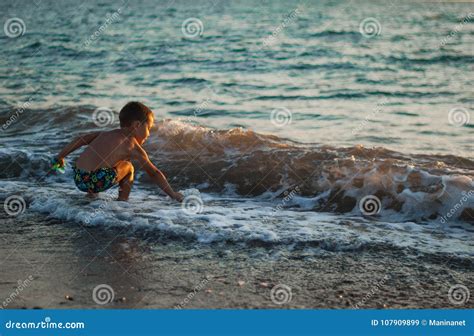 Un Ragazzino Che Gioca Nella Sabbia Sul Mar Nero Dentro Spruzza Delle Onde Al Tramonto Del