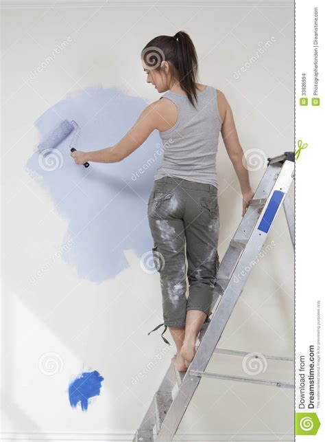 Woman Painting Wall With Paintroller While Standing On