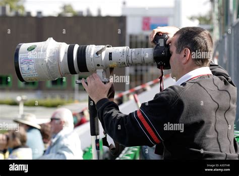 SPORTS PHOTOGRAPHER WITH A LONG CANON TELEPHOTO LENS PHOTOGRAPHING A Stock Photo: 10755346 - Alamy