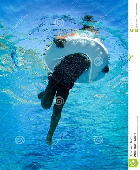 Underwater Photo Of Girl Swimming In Pool With Circular Floating Stock