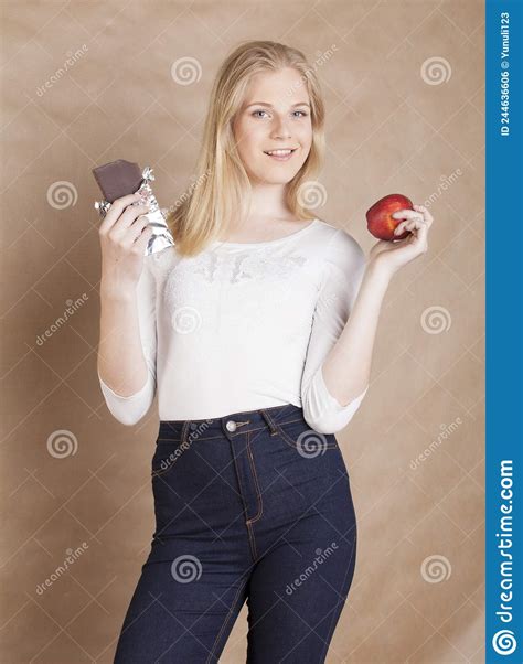 Young Beauty Blond Teenage Girl Eating Chocolate Smiling Choice Between Sweet And Apple Stock