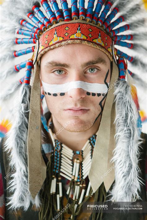 Young Man With Line On Face Posing In Traditional Native American