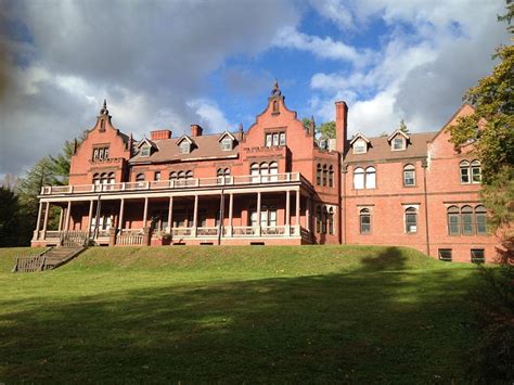 A Large Red Brick Building Sitting On Top Of A Lush Green Field Under A