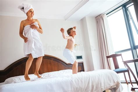Mother And Son Jump On Bed In Luxury Hotel Room Stock