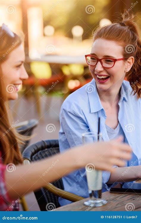 Two Smiling Female Friends Talking Drinking Coffee Outdoors In The