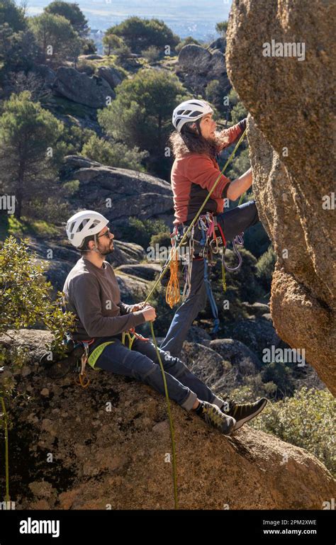 Two Young Adults Working Together To Climb A Granite Wall Rock