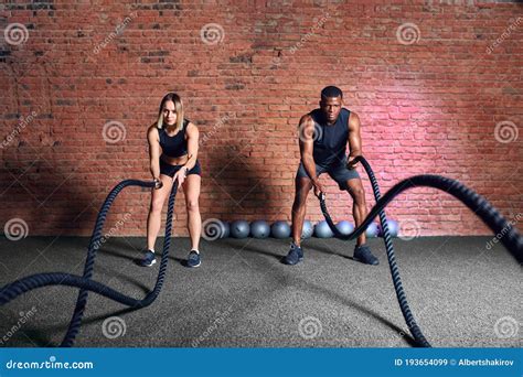 Multiethnic People Exercising With Battle Ropes At Gym Couple Training