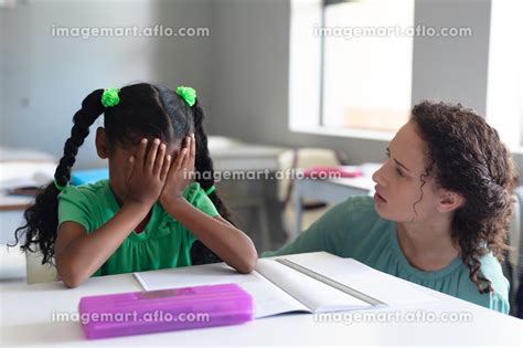 Caucasian Young Female Teacher Looking At African American Elementary