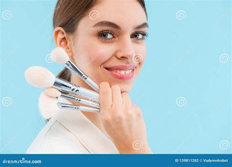 Beautiful Young Woman Posing Over Blue Background Holding Makeup