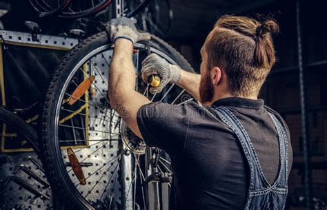 Mechanic Repairing Bicycle Wheel Tire In A Workshop Stock Photo