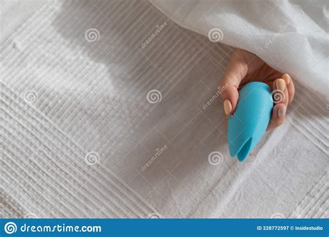 A Faceless Woman Lies In Bed Under A Blanket Holding A Clitoral