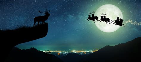 Silhouette Of Santa Claus Flying Over The Full Moon Stock Photo