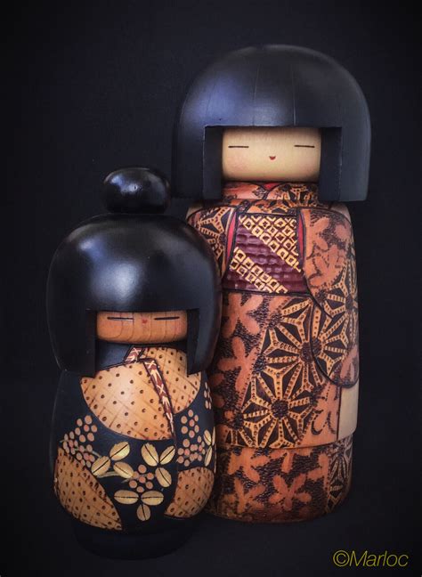 Two Wooden Dolls Sitting Next To Each Other