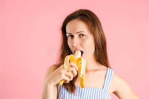 Hungry Brunette Bites A Banana On A Pink Background Stock Image Image